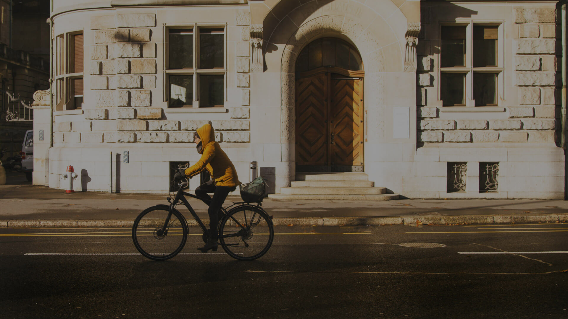 kolesarka z rumeno jakno kolesari po mestnih ulicah